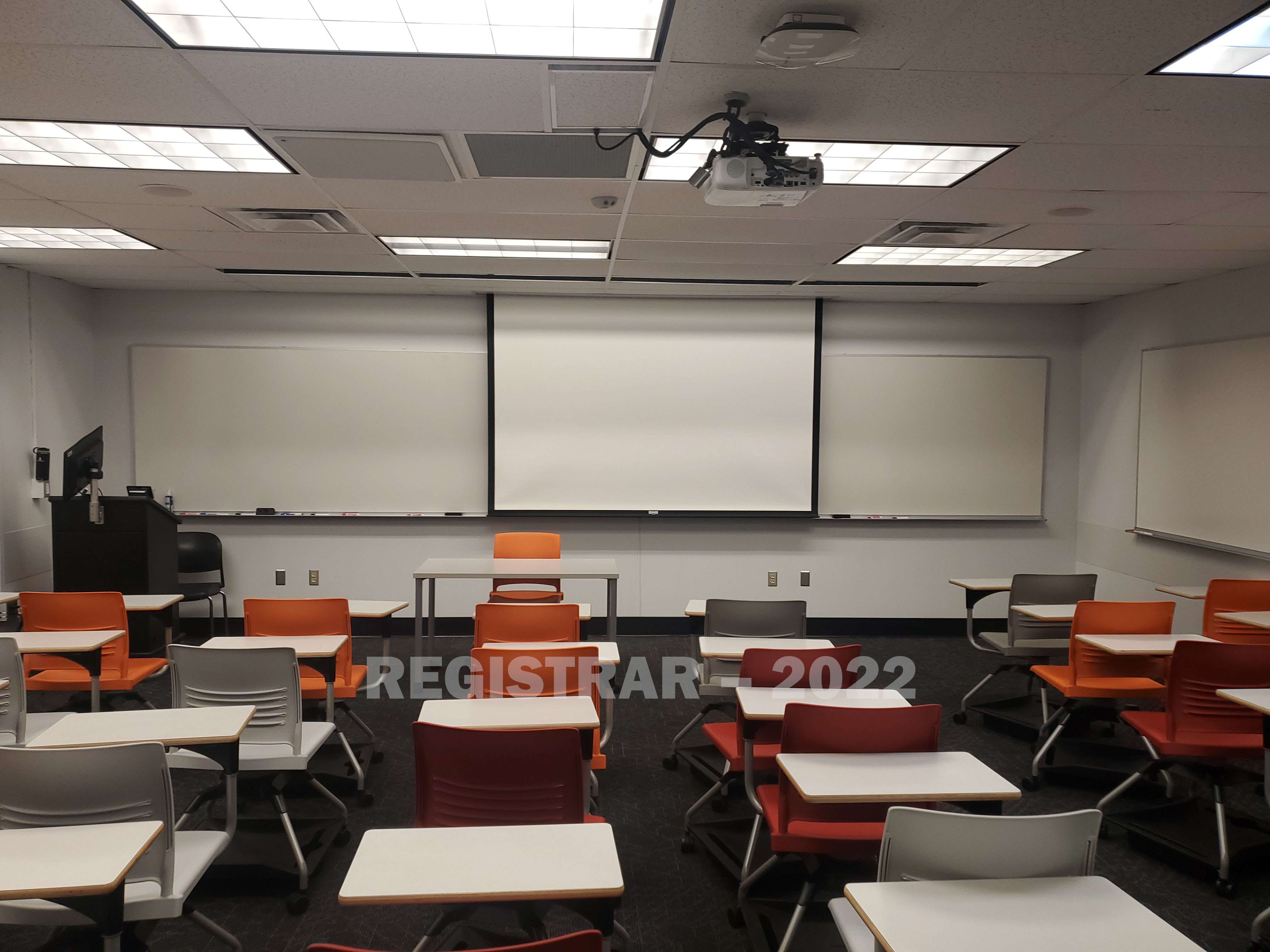 Journalism Building room 274 view from the back of the room with projector screen down